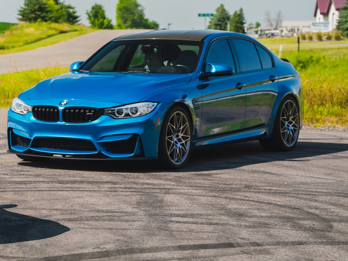 Blue BMW sedan photographed on an open paved area.