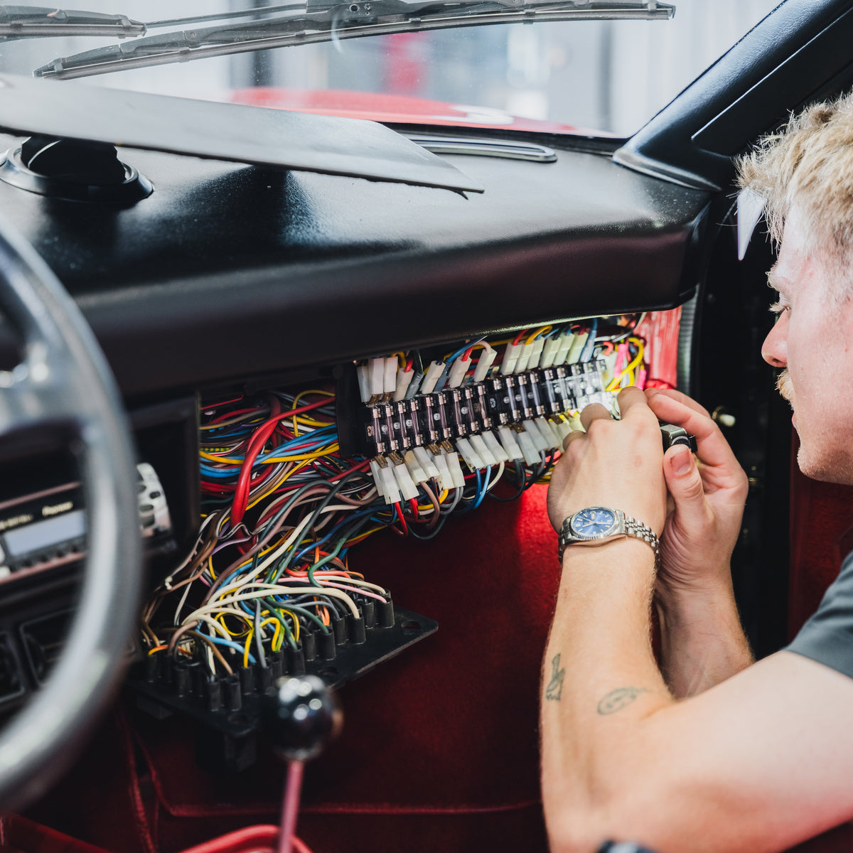 Technician beside an exposed electrical panel inside a Ferrari cabin.