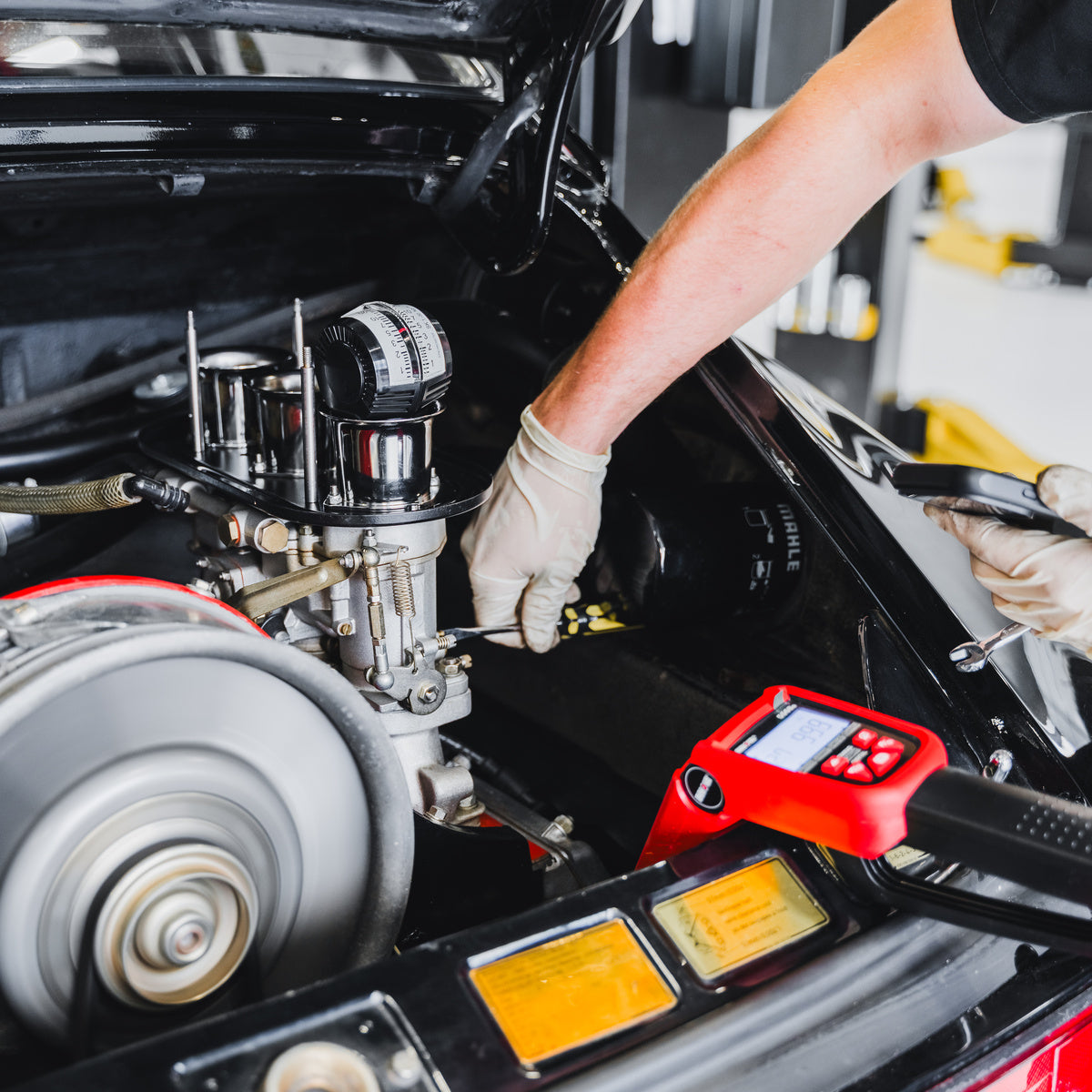 Gloved technician working beside an air-cooled Porsche engine.