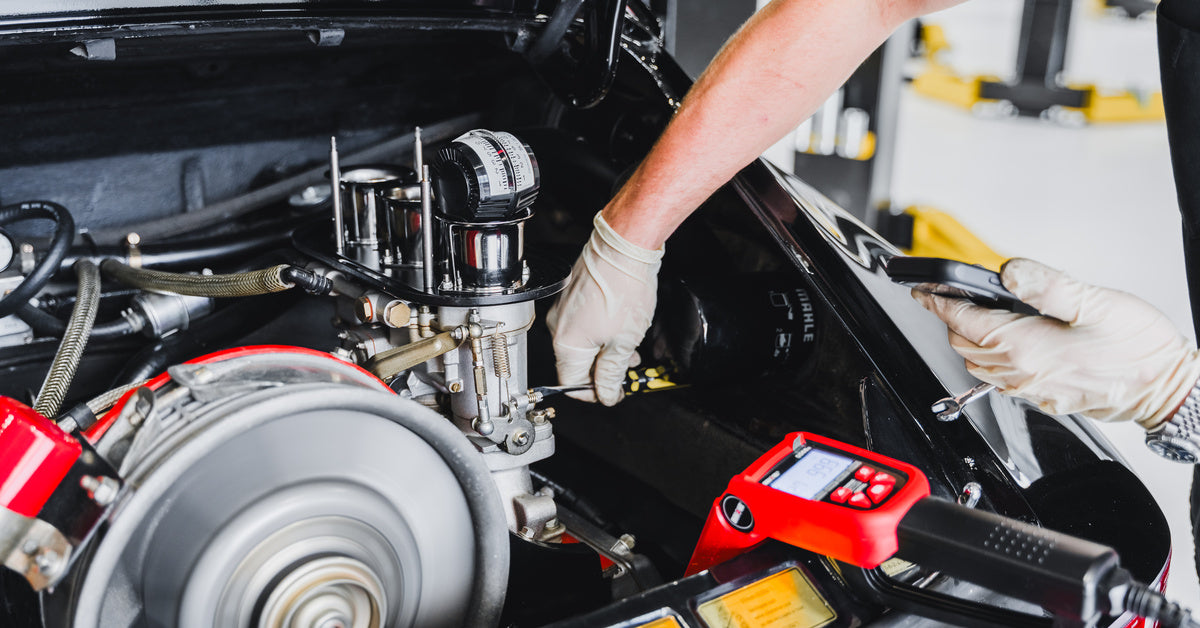 Technician performing diagnostic measurements on an air-cooled Porsche engine